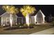 Night view of a beautifully lit home with palm trees, lush green lawn, and a well-maintained front yard at 7205 Spoleto Dr., Myrtle Beach, SC 29572