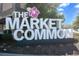 Large white 'The Market Common' sign with a pink hibiscus flower, set against a backdrop of trees at 730 Farrow Pkwy. # D, Myrtle Beach, SC 29577