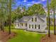 Beautiful white home featuring black shutters, complemented by a lush green lawn and mature trees at 19 Coventry Pl., Pawleys Island, SC 29585