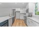 Open kitchen with white cabinetry, stainless steel appliances, quartz countertops, and wood-look flooring at 19 Coventry Pl., Pawleys Island, SC 29585