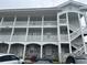 Building exterior featuring light-blue siding, gray-brick accents, and white-columned balconies at 4639 Wild Iris Dr. # 43-204, Myrtle Beach, SC 29577