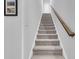 Carpeted staircase with wood railing leads to the upper level past a wall with framed art at 5606 Whitebark Dr., Myrtle Beach, SC 29577