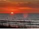 Ocean view at sunrise with sun just peeking over the horizon and some sea grass in view at 108 Ocean Blvd. N # 101, North Myrtle Beach, SC 29582