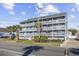 Condo building with three stories and multiple balconies, surrounded by palm trees at 1210 N Ocean Blvd. # 105, Surfside Beach, SC 29575