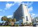Striking exterior view of the hotel with blue-gray balconies and palm trees under a bright blue sky at 2001 S Ocean Blvd. # 1505, Myrtle Beach, SC 29577