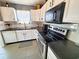 Well-lit kitchen with white cabinets, black countertops, and stainless steel appliances, including dishwasher at 221 Black Bear Rd., Myrtle Beach, SC 29588