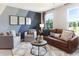 Bright living room with a brown leather sofa, armchairs, patterned wall, and large windows at 324 Mayflower Dr., Calabash, NC 28467