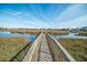 Scenic view of a wooden dock leading to waterfront homes with blue skies and marshland at 358 Salt Marsh Circle # 10-A, Pawleys Island, SC 29585