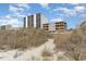 Exterior of multi-story condo buildings on a sunny day from beach access point at 4305 S Ocean Blvd. # 301, North Myrtle Beach, SC 29582