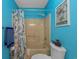 Bright blue bathroom with shower, toilet, colorful shower curtain, and decorative artwork at 4500 S Ocean Blvd. # 9-B, North Myrtle Beach, SC 29582