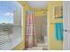 Bright yellow bathroom with a shower with colorful curtain, window, and neutral flooring at 4500 S Ocean Blvd. # 9-B, North Myrtle Beach, SC 29582