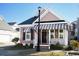 Charming single-Gathering home with a black front door and a striped awning at 676 Johnson Ave., Myrtle Beach, SC 29577