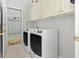 Bright laundry room featuring white cabinets, tile flooring, washer and dryer, and garage access at 6904 Gina Ct., Myrtle Beach, SC 29588