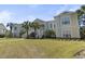 This is the exterior of a yellow townhouse with palm trees and white stairways at 77 Tern Pl. # 202, Pawleys Island, SC 29585
