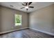 Bedroom with neutral walls, wood-look flooring, ceiling fan, and a window overlooking lush greenery at 646 Sunny Pond Ln., Aynor, SC 29511