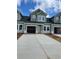 New construction townhome showcases a light green exterior, black roof, and spacious two-car garage, bathed in natural light at 1997 Wild Indigo Circle Nw # 7, Calabash, NC 28467