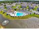 Aerial view of community pool with clubhouse, surrounding homes, and pond with a fountain at 1415 Gooseneck Place # 101, Murrells Inlet, SC 29576