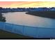 Scenic pond view at sunset with a white fence in the foreground and neighborhood homes in the background at 256 Copper Leaf Dr., Myrtle Beach, SC 29588