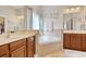 Bright bathroom featuring a soaking tub between and sink vanities with wood cabinets at 432 Highfield Loop, Myrtle Beach, SC 29579