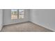 A carpeted bedroom has two windows with a view to the street and light gray walls at 48 Cape Point Dr., Conway, SC 29527