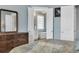 Airy bedroom showcasing an en suite bathroom through double doors, complemented by a warm wood dresser at 6004 Flowerdale Ct., Myrtle Beach, SC 29579