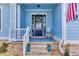 Inviting front porch with rocking chairs, brick steps, blue painted floors and front door with a wreath at 6004 Flowerdale Ct., Myrtle Beach, SC 29579