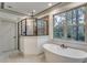 Modern bathroom features a soaking tub, glass shower, and a large window with natural light and wooded views at 6013 Blease Ct., Myrtle Beach, SC 29588