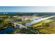 Aerial view featuring a waterway, bridge, golf course, and the city skyline in the distance at 6121 Bolsena Place, Myrtle Beach, SC 29572