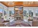Bright sunroom featuring a stone fireplace, comfortable seating, and large windows offering scenic backyard views at 6121 Bolsena Place, Myrtle Beach, SC 29572