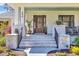 Inviting front porch with brick stairs and pillars, beautiful plants, and a seating area at 644 Whispering Pines Ct., Murrells Inlet, SC 29576
