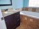 Bathroom featuring a dark vanity, granite countertop, soaking tub with tiled surround at 6654 Wisteria Dr., Myrtle Beach, SC 29588