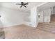 View of the living room showcasing neutral carpeting, a ceiling fan, and staircase at 7300 Porcher Dr. # 11, Myrtle Beach, SC 29572