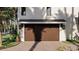 A close-up of the wooden garage door, with dark trim and sconce lighting in the front of the home at 918 Strand Ave., North Myrtle Beach, SC 29582