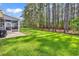 Expansive grassy backyard, featuring trees, a black fence, a screened in porch and a patio with grill at 329 Lake Mist Ct., Longs, SC 29568