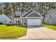 Charming home featuring two-car garage, inviting entryway, manicured lawn, and elegant landscaping at 329 Lake Mist Ct., Longs, SC 29568