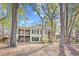 Rear exterior of a condo with screened porches framed by mature trees and foliage at 95 Weehawka Way # 2, Pawleys Island, SC 29585