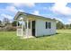 A small, white, wooden building with a dark door and window shutters, on a green grassy lot at 1136 Knotty Branch Rd., Conway, SC 29527