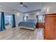 Large primary bedroom featuring a tray ceiling, a ceiling fan, hardwood floors, and windows with blue curtains at 138 Cooper River Rd., Myrtle Beach, SC 29588