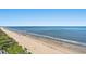 Scenic beach view with light sand, blue water, and lush greenery in the background at 1625 S Ocean Blvd. # 1510, North Myrtle Beach, SC 29582