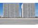 Two towers of luxury beachfront condos rise above a sandy beach with a clear blue sky at 1625 S Ocean Blvd. # 1510, North Myrtle Beach, SC 29582