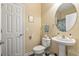 Bright bathroom featuring a pedestal sink, round mirror, and toilet in a neutrally decorated space at 173 Knight Circle # 1, Pawleys Island, SC 29585