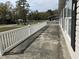 Covered porch with white railing provides shade and a relaxing outdoor space with black shutters and vinyl siding at 301 Byrnes Circle, Johnsonville, SC 29555