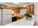 Cozy kitchen featuring wood cabinets, white counter tops, stove, refrigerator, microwave, and a mosaic backsplash at 500 Fairway Village Dr. # 5D, Myrtle Beach, SC 29588