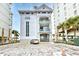 Exterior view of the building with well-maintained landscaping, palm trees, and ample parking space at 6253 Catalina Dr. # 214, North Myrtle Beach, SC 29582
