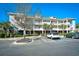 A multi-story condo building featuring stairs, white railings, and palm trees set against a clear blue sky at 6253 Catalina Dr. # 214, North Myrtle Beach, SC 29582