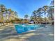 Community pool featuring clear blue water, sun loungers, and towering trees at 86 Old Barge Dr., Pawleys Island, SC 29585
