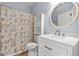 A bathroom with a seashell-themed shower curtain, white vanity, and round mirror at 5022 Belleglen Ct. # 202, Myrtle Beach, SC 29579