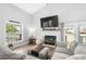 Cozy living room with a fireplace, gray sectional sofa, large window, and a mounted television at 160 Shipmaster Ave., Pawleys Island, SC 29585