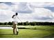 Golfer tees off on a green golf course with clear blue sky and fluffy white clouds in the background on a sunny day at 247 Warner Crossing Way, Loris, SC 29569