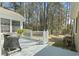 Back porch view features white railings, grill, an outside table, and view to treed backyard at 2 Sunrise Ct., Carolina Shores, NC 28467